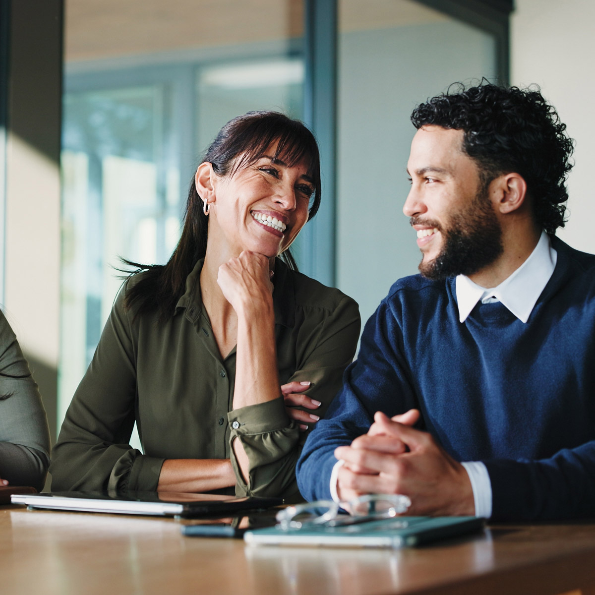 woman looking at man smiling, conversing during meeting
